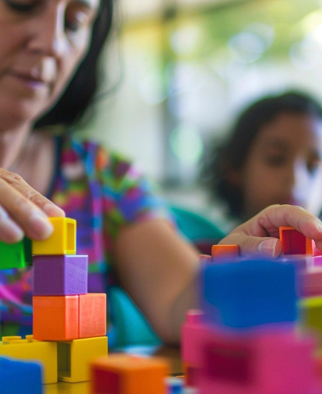 Mãe e criança brincando com blocos coloridos