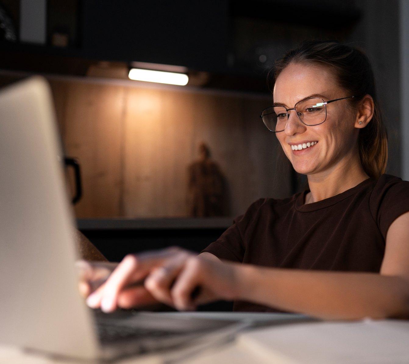 Profissional de saúde sorrindo enquanto acompanha pacientes no notebook